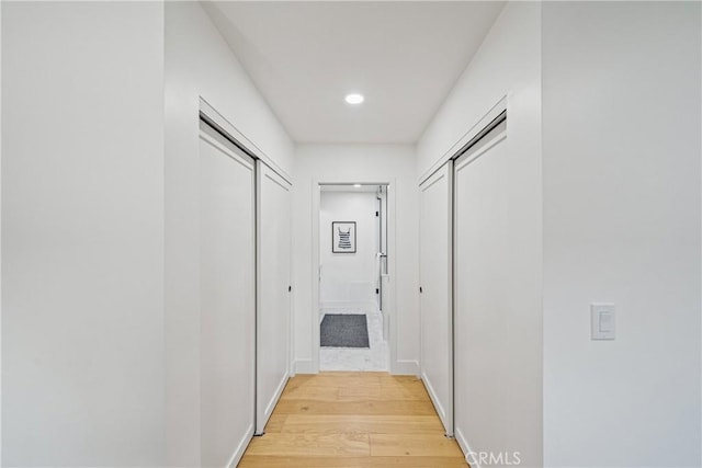 corridor featuring light wood-style flooring, baseboards, and recessed lighting