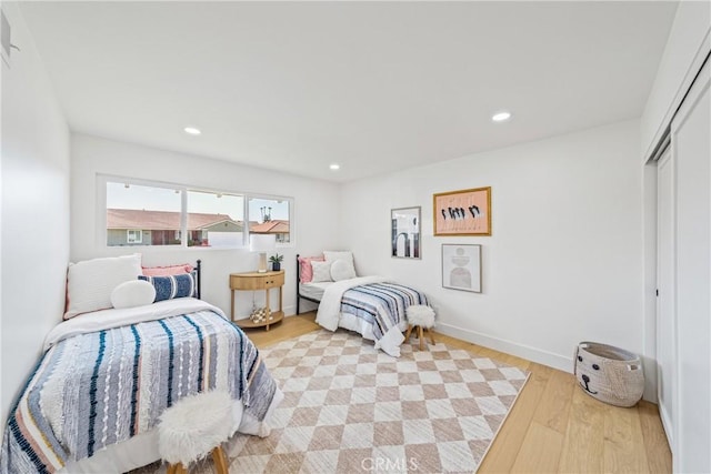 bedroom featuring light wood-type flooring, baseboards, a closet, and recessed lighting