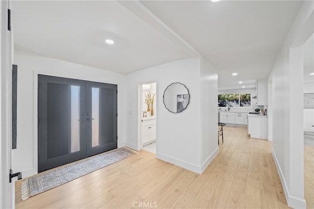 entryway with french doors, light wood-type flooring, recessed lighting, and baseboards