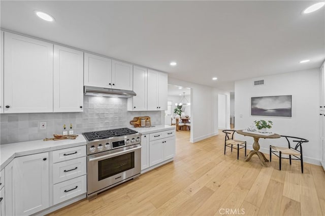 kitchen with light wood finished floors, visible vents, stainless steel range, light countertops, and under cabinet range hood