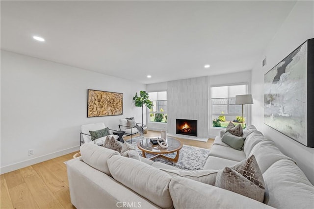 living area with light wood-type flooring, a fireplace, baseboards, and recessed lighting