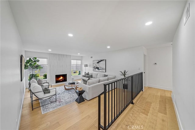 living area with baseboards, a fireplace, light wood-style flooring, and recessed lighting