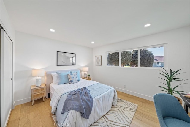 bedroom with baseboards, light wood finished floors, a closet, and recessed lighting