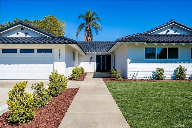 view of front of house with a garage, a front yard, a tiled roof, and stucco siding