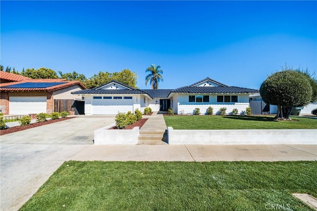 ranch-style house featuring a tile roof, concrete driveway, a front yard, fence, and a garage