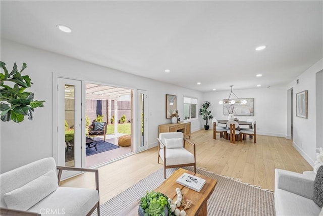 living area with baseboards, light wood-type flooring, a notable chandelier, and recessed lighting