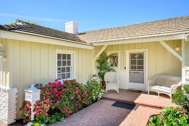 doorway to property featuring a chimney, a patio, and brick siding