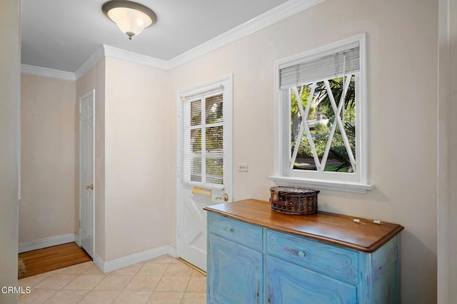 doorway featuring light tile patterned flooring, crown molding, and baseboards