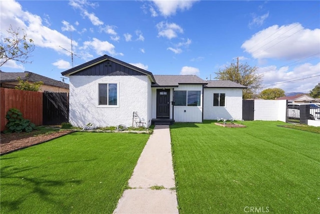 view of front of house featuring stucco siding, fence, and a front yard