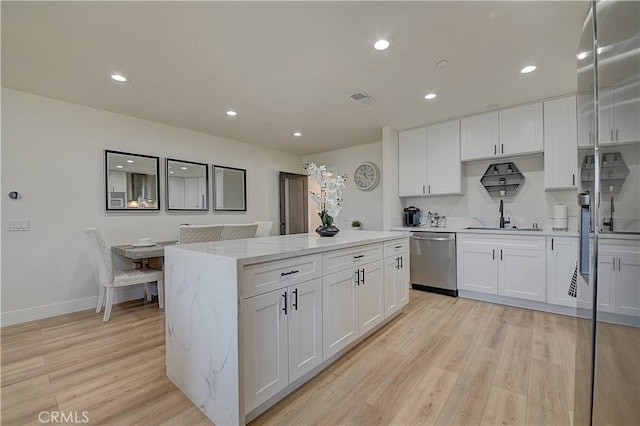 kitchen with light wood-type flooring, a center island, visible vents, and dishwasher