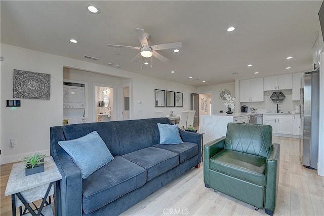 living area with baseboards, visible vents, stacked washer / dryer, light wood-style floors, and recessed lighting