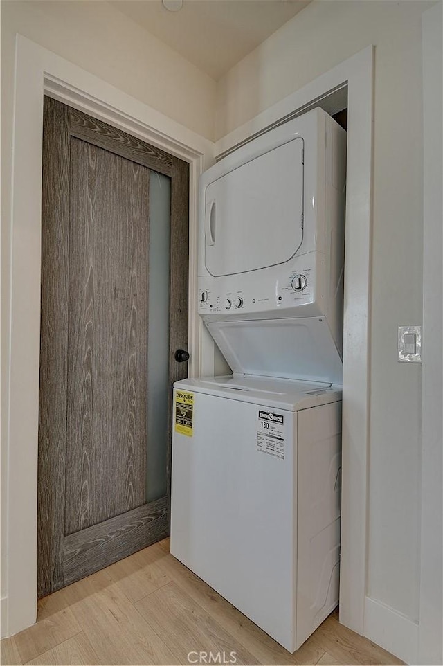 laundry area with light wood-type flooring, stacked washing maching and dryer, and laundry area