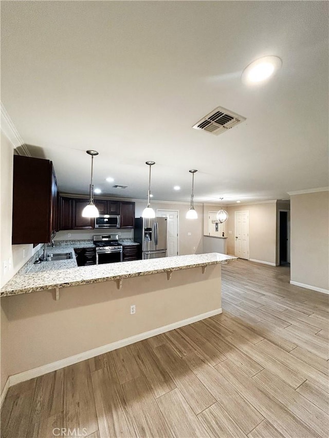 kitchen with visible vents, light wood-style flooring, light stone counters, stainless steel appliances, and a sink