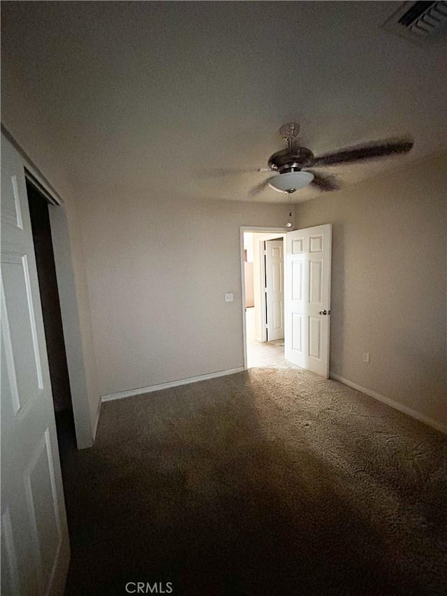 carpeted spare room with ceiling fan, visible vents, and baseboards