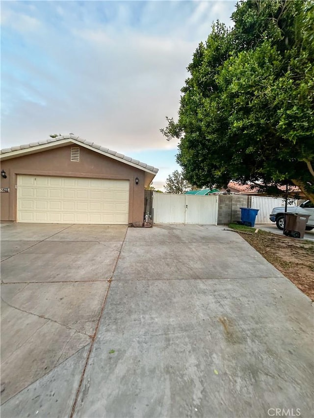 view of front of house featuring a garage, fence, a gate, and stucco siding