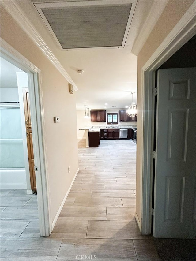 hallway with baseboards, ornamental molding, and wood finish floors