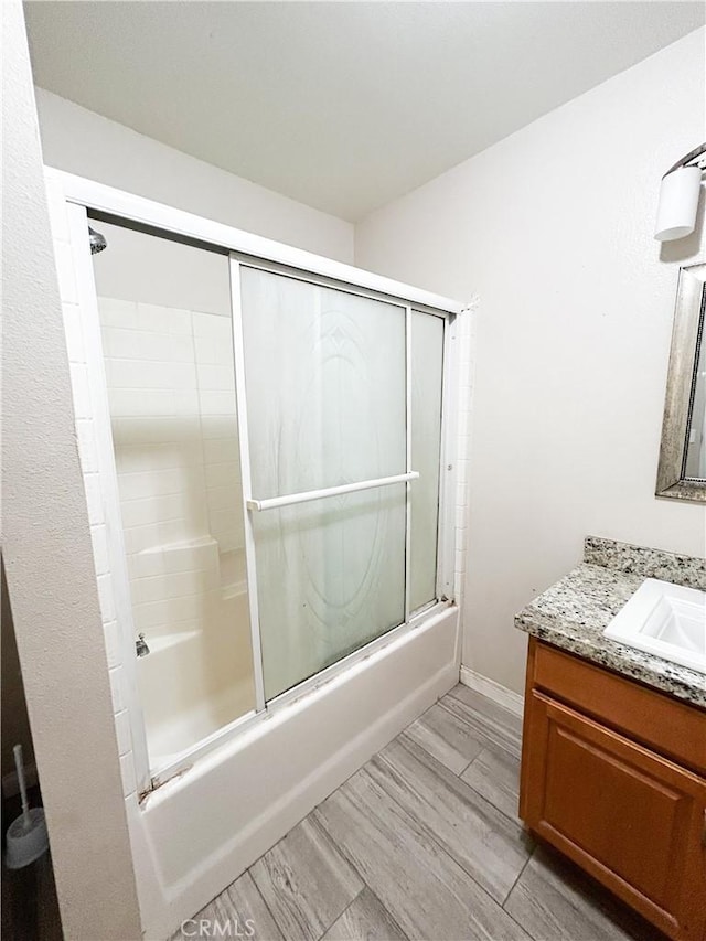 full bath featuring enclosed tub / shower combo, baseboards, and vanity
