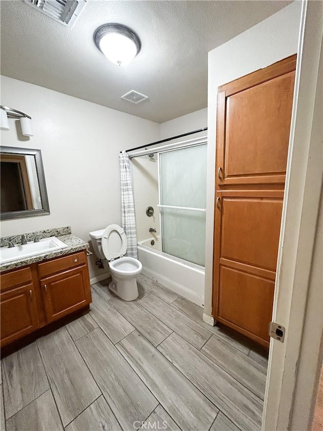 full bathroom featuring visible vents, toilet, vanity, and combined bath / shower with glass door