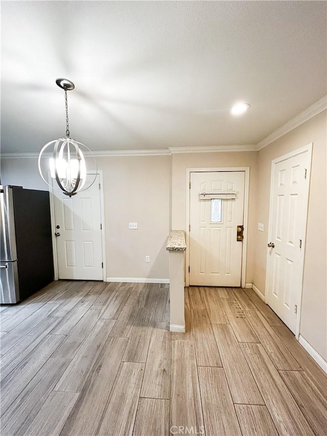 entrance foyer with baseboards, a notable chandelier, light wood-style flooring, and crown molding