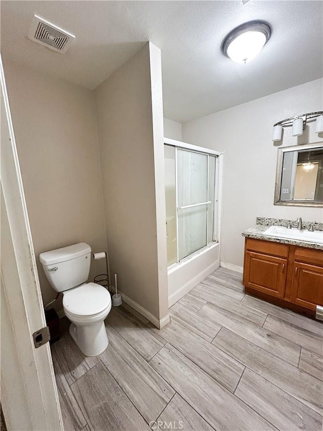 full bathroom with wood finish floors, visible vents, toilet, enclosed tub / shower combo, and vanity