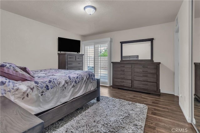 bedroom with a textured ceiling, dark wood-type flooring, and baseboards