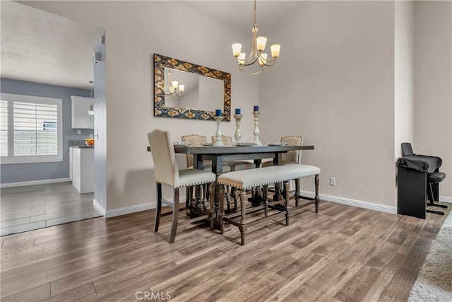 dining area with a chandelier, baseboards, and wood finished floors