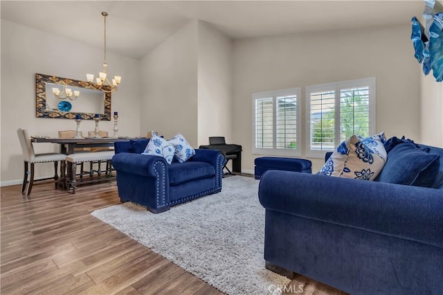 living area with a chandelier, high vaulted ceiling, baseboards, and wood finished floors