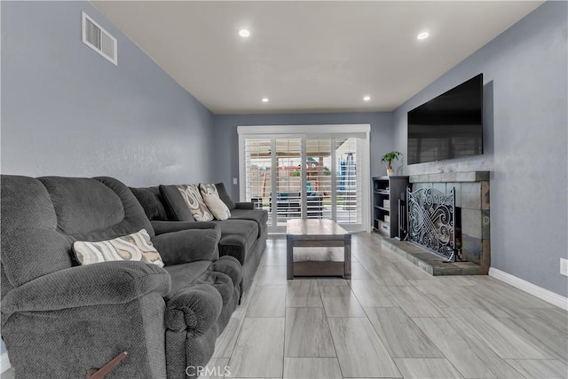 living room featuring recessed lighting, visible vents, baseboards, and a tile fireplace