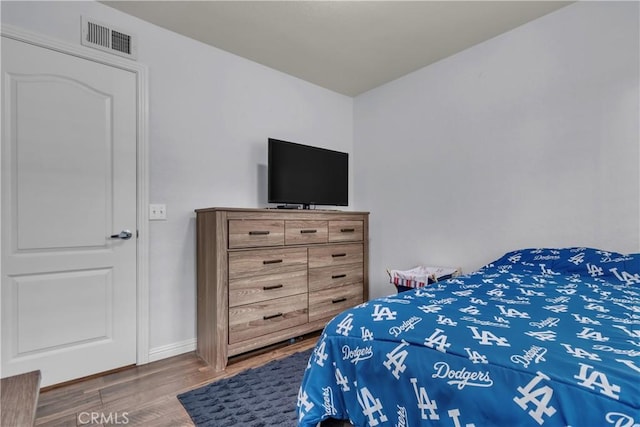 bedroom featuring wood finished floors, visible vents, and baseboards