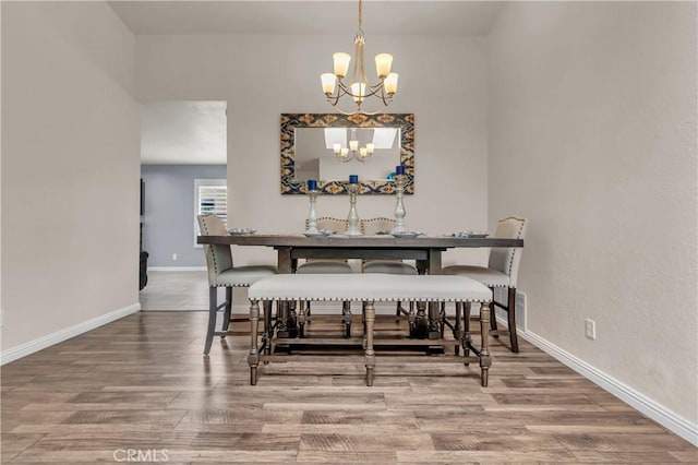 dining area with baseboards, an inviting chandelier, and wood finished floors