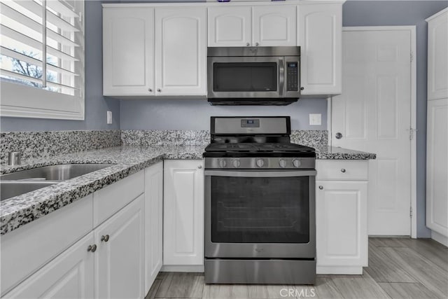 kitchen with light stone counters, white cabinets, and appliances with stainless steel finishes