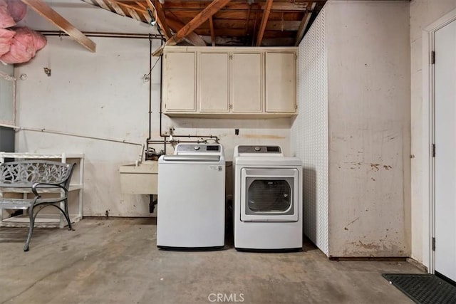 washroom with a sink, cabinet space, and washer and dryer