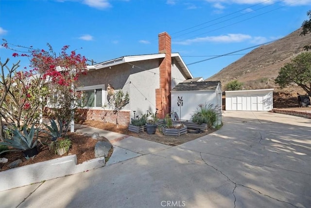 view of property exterior with a chimney, concrete driveway, and stucco siding