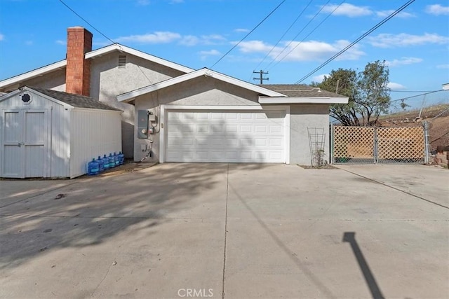 view of side of home featuring an outbuilding, fence, an attached garage, and stucco siding