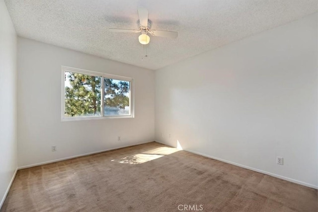 empty room with carpet flooring, ceiling fan, a textured ceiling, and baseboards