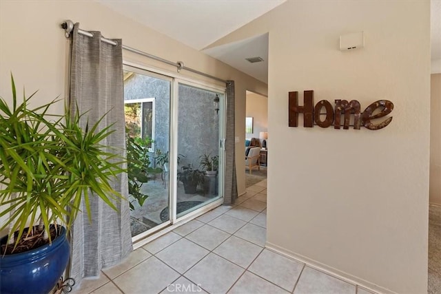 doorway to outside with lofted ceiling, light tile patterned floors, and plenty of natural light