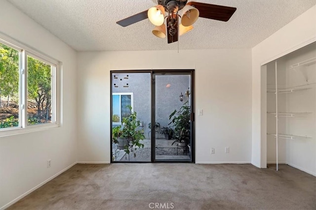 carpeted empty room with ceiling fan, baseboards, and a textured ceiling