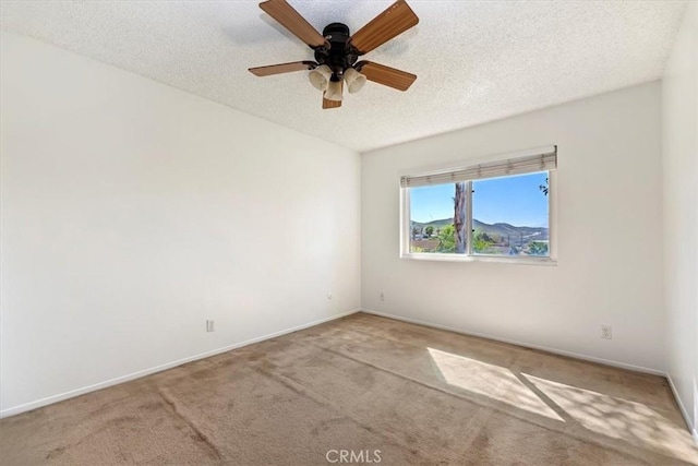 empty room featuring a ceiling fan, carpet, baseboards, and a textured ceiling