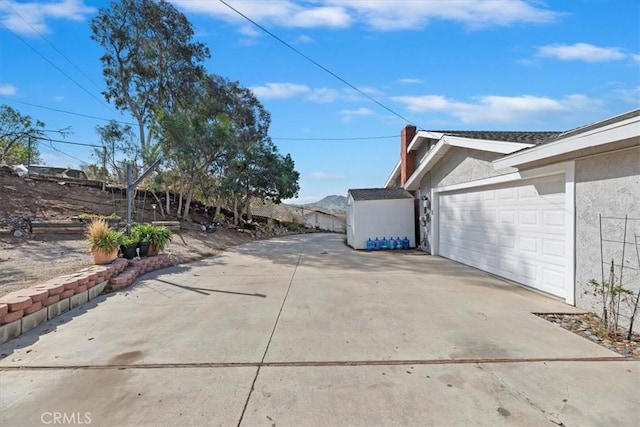 exterior space with an attached garage, fence, driveway, stucco siding, and a chimney