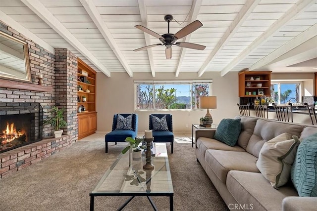 living room with plenty of natural light, a brick fireplace, beamed ceiling, and carpet