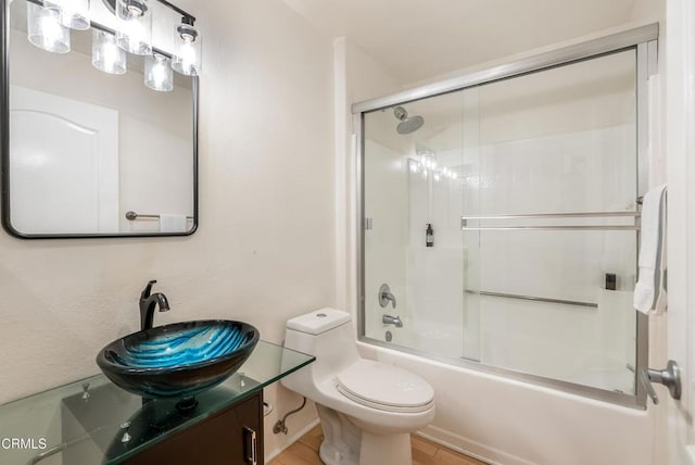 bathroom with vanity, toilet, and bath / shower combo with glass door