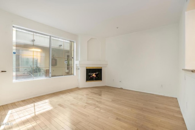 unfurnished living room featuring a glass covered fireplace and hardwood / wood-style floors