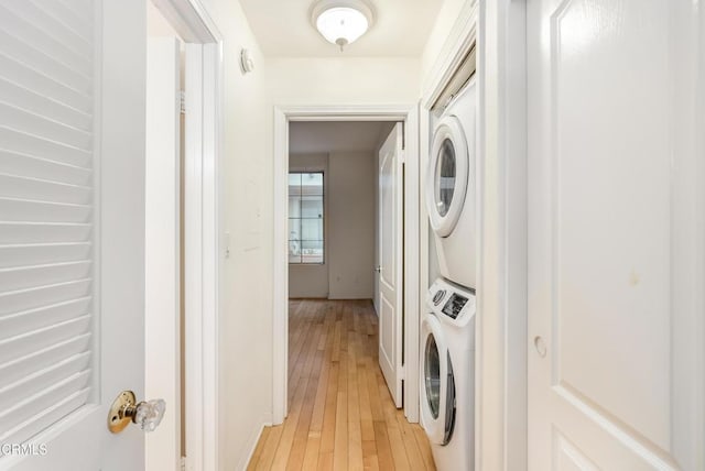 clothes washing area with laundry area, light wood-style flooring, and stacked washer / drying machine