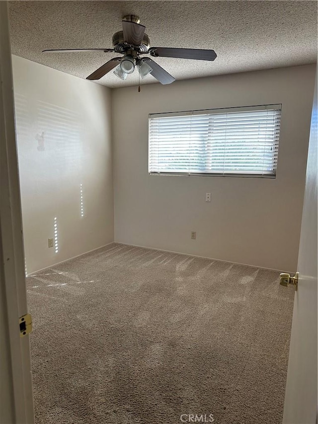 carpeted empty room with ceiling fan and a textured ceiling