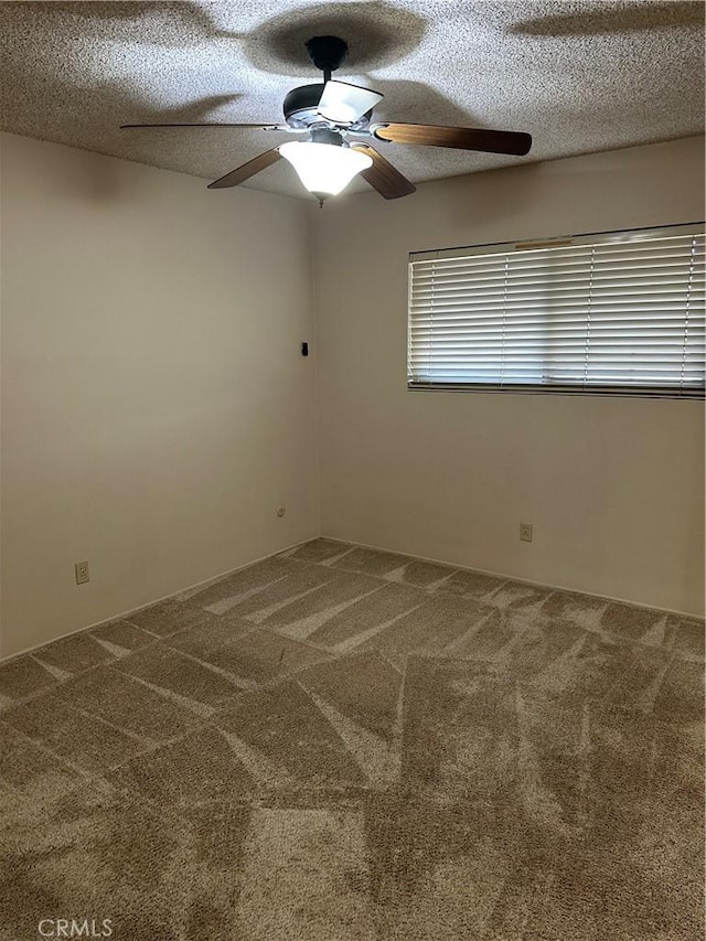 carpeted spare room with a textured ceiling and a ceiling fan