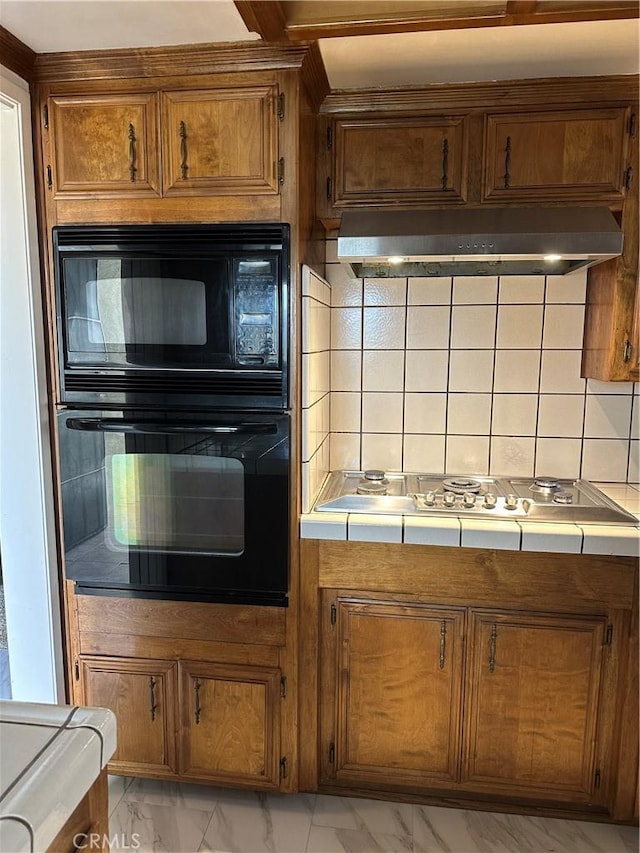 kitchen with tile countertops, black appliances, marble finish floor, and under cabinet range hood