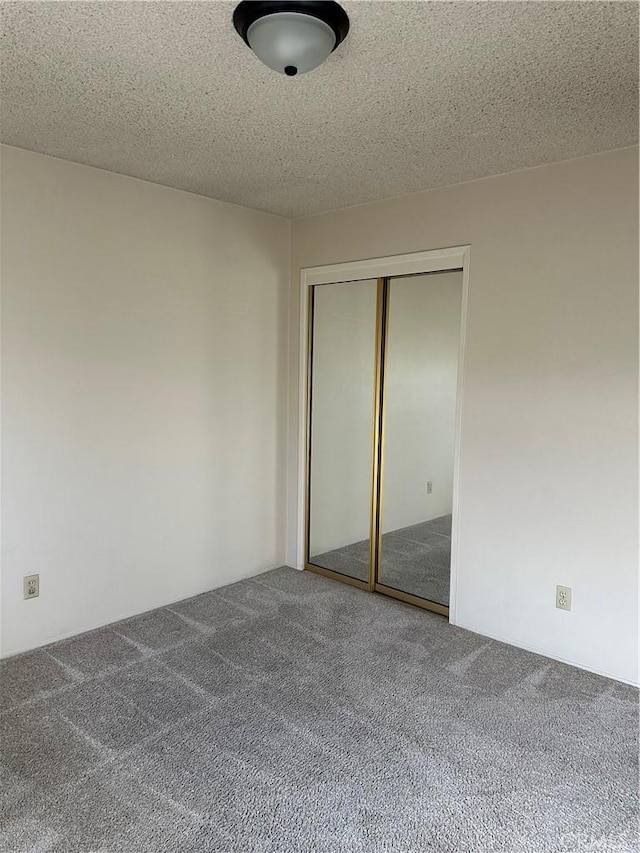 unfurnished bedroom with carpet floors, a closet, and a textured ceiling