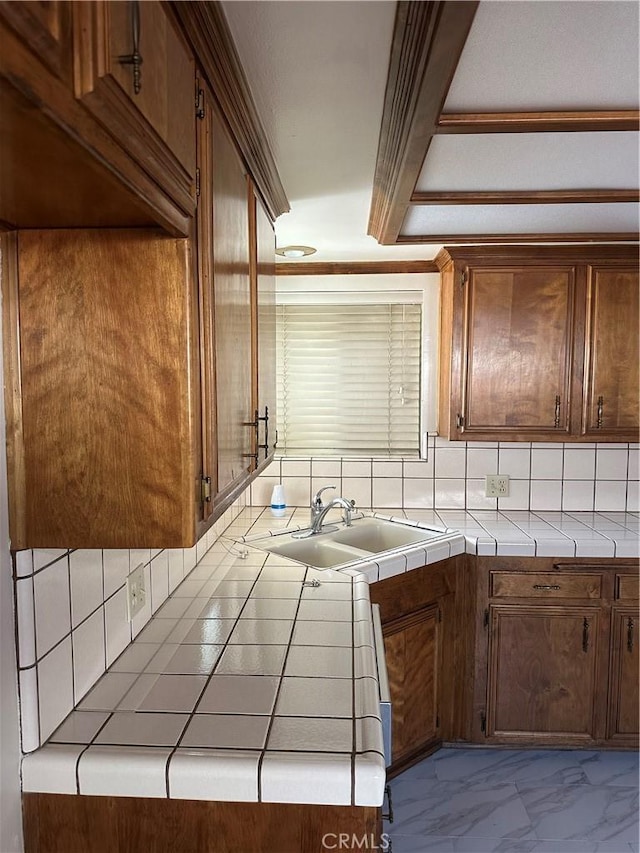 kitchen featuring marble finish floor, backsplash, a sink, and tile counters