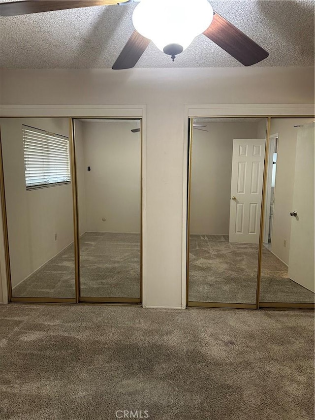 unfurnished bedroom featuring carpet, a textured ceiling, and two closets