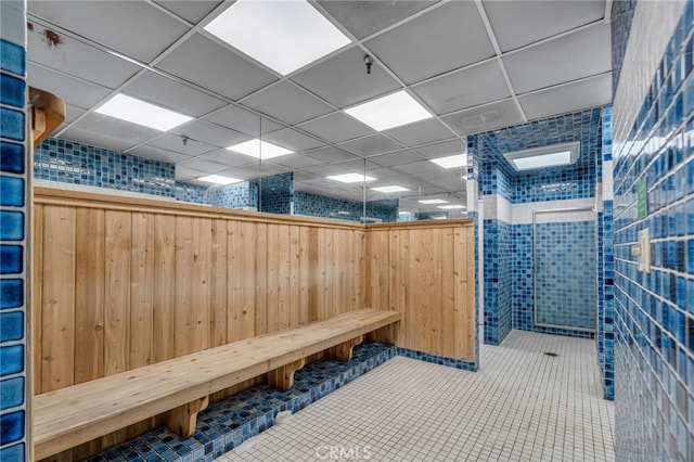 interior space with tile patterned floors, a drop ceiling, and tiled shower